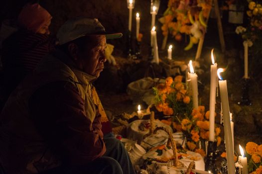 Man sitting among candles during Day of the Dead celebration in Janitzio, Mexico.