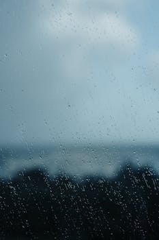 Close-up of rain on a glass window with blurred background. Perfect for weather-related themes.