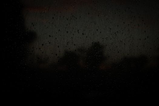 Dark window with water droplets creating a moody atmosphere.