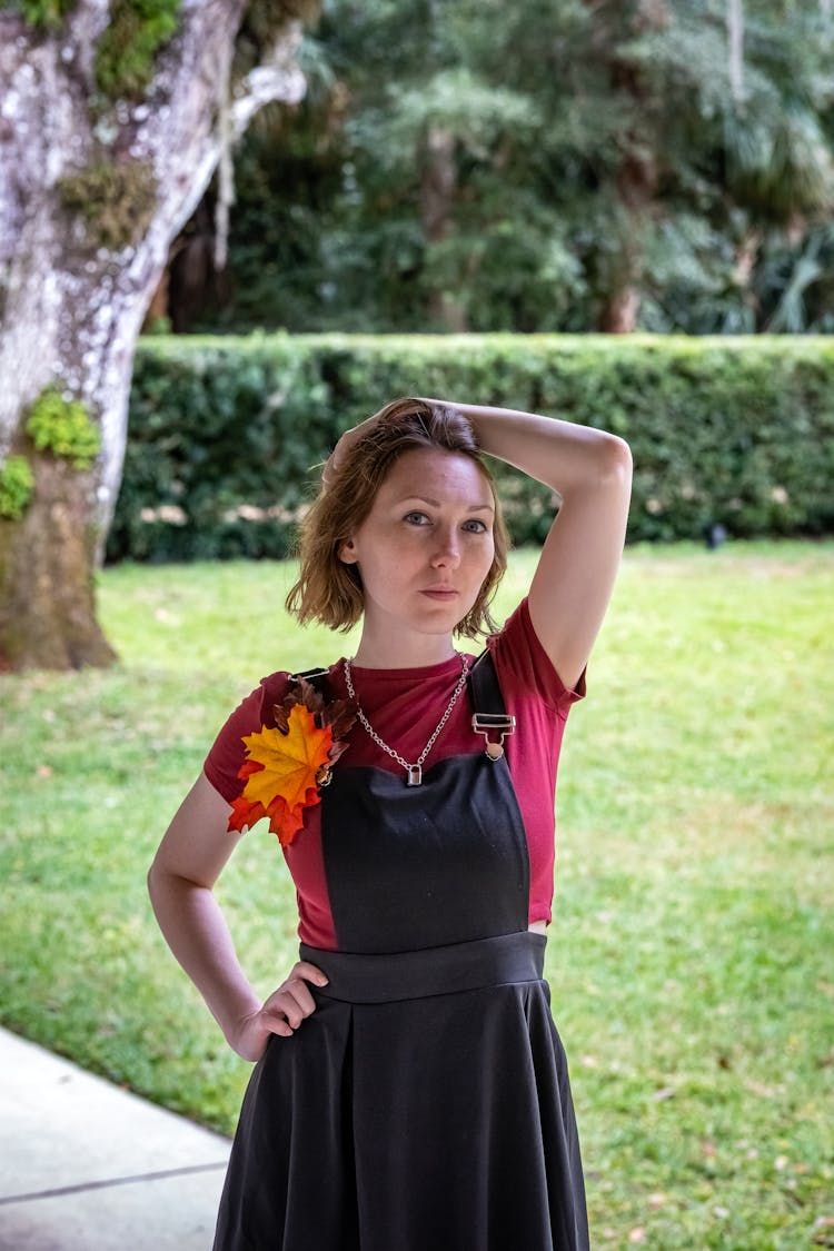 A Woman In Black Jumper Dress Standing Near The Green Grass Field