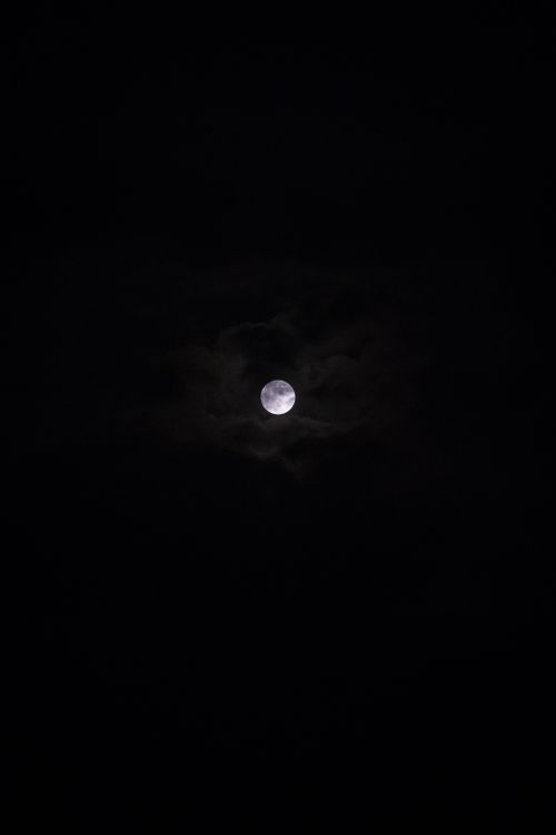 Free A clear view of the full moon surrounded by dark clouds at night. Stock Photo
