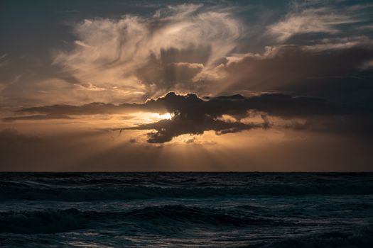 A captivating sunset with dramatic clouds over the ocean, showcasing nature's beauty.