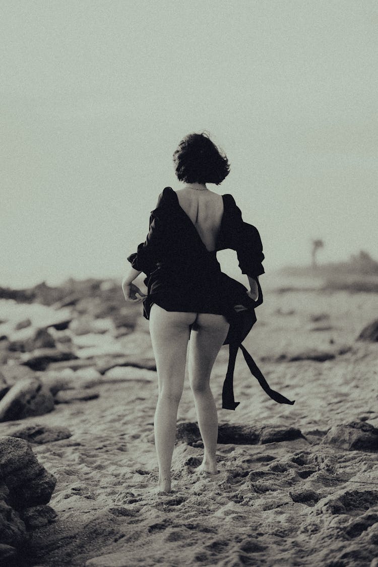 Grayscale Photo Of A Woman Removing Clothes In The Beach