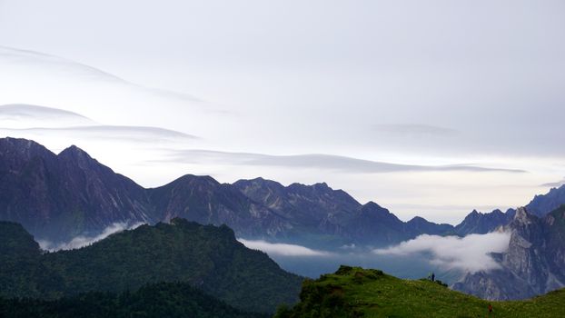 Serene mountain landscape with mist and clouds, offering a peaceful view.