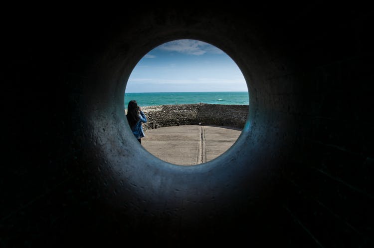 Person Standing Near Breakwater Tunnel Overlooking The Sea