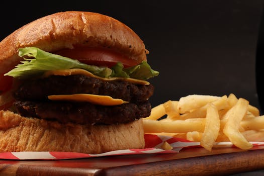 Mouthwatering close-up of a cheeseburger with lettuce, tomato, and fries.
