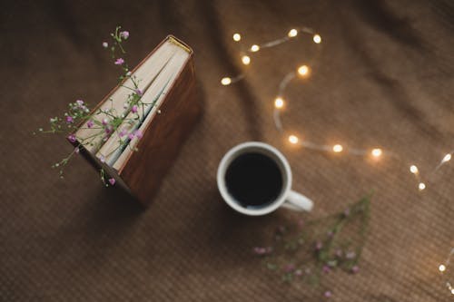 A Cup of Coffee Near the Book with Flowers