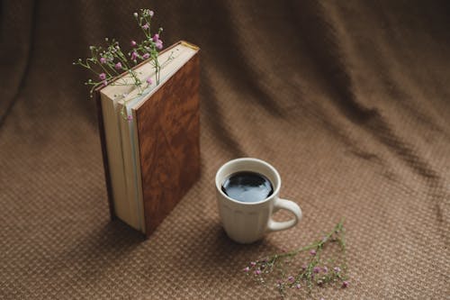 A Cup of Coffee near a Brown Book