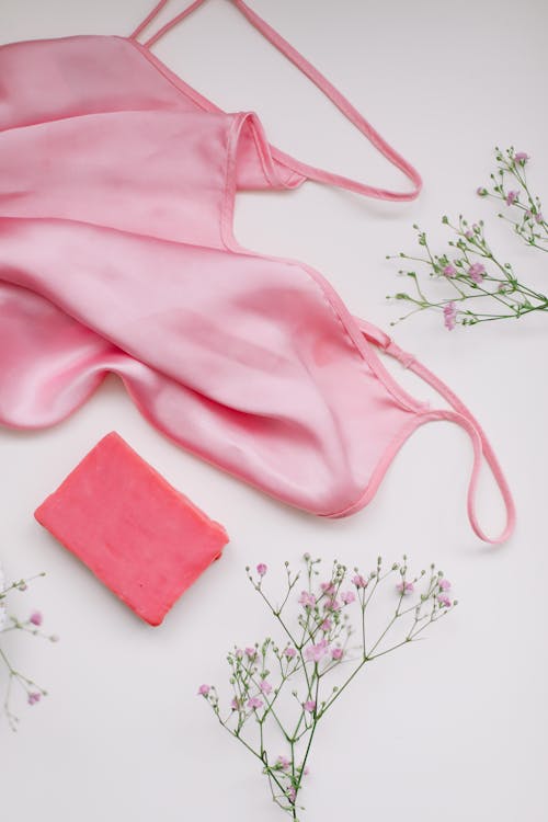 A Pink Clothes on White Surface Near the Flowers and Pink Bar Soap