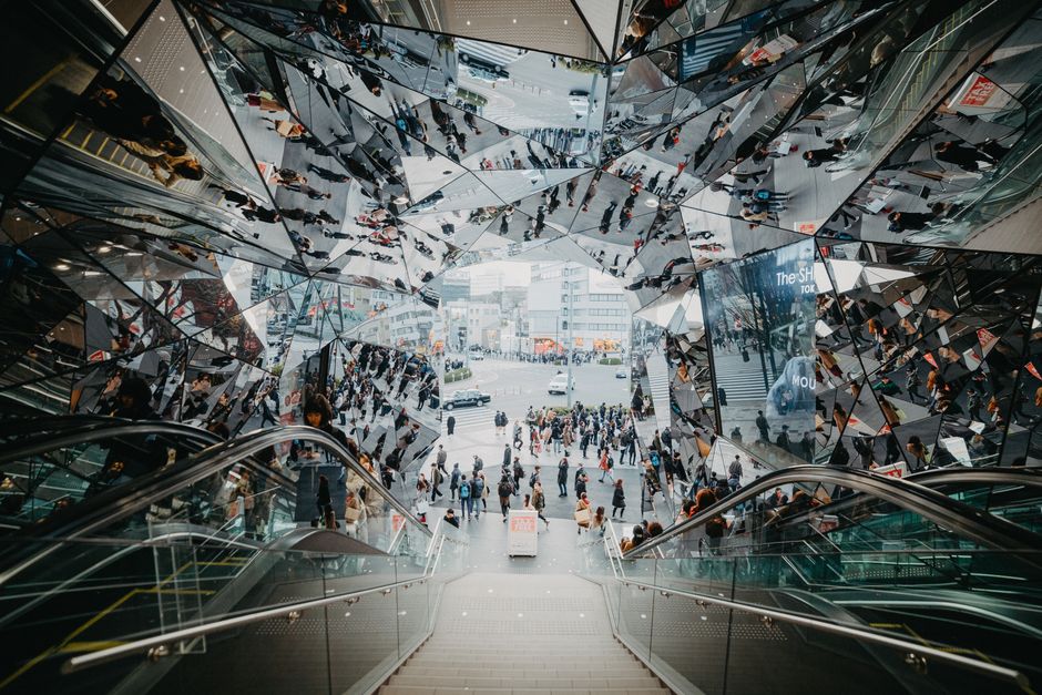 鏡の反射がある東京のショッピングモールでのエスカレーターとモダンな建築の高い角度からの眺め。
