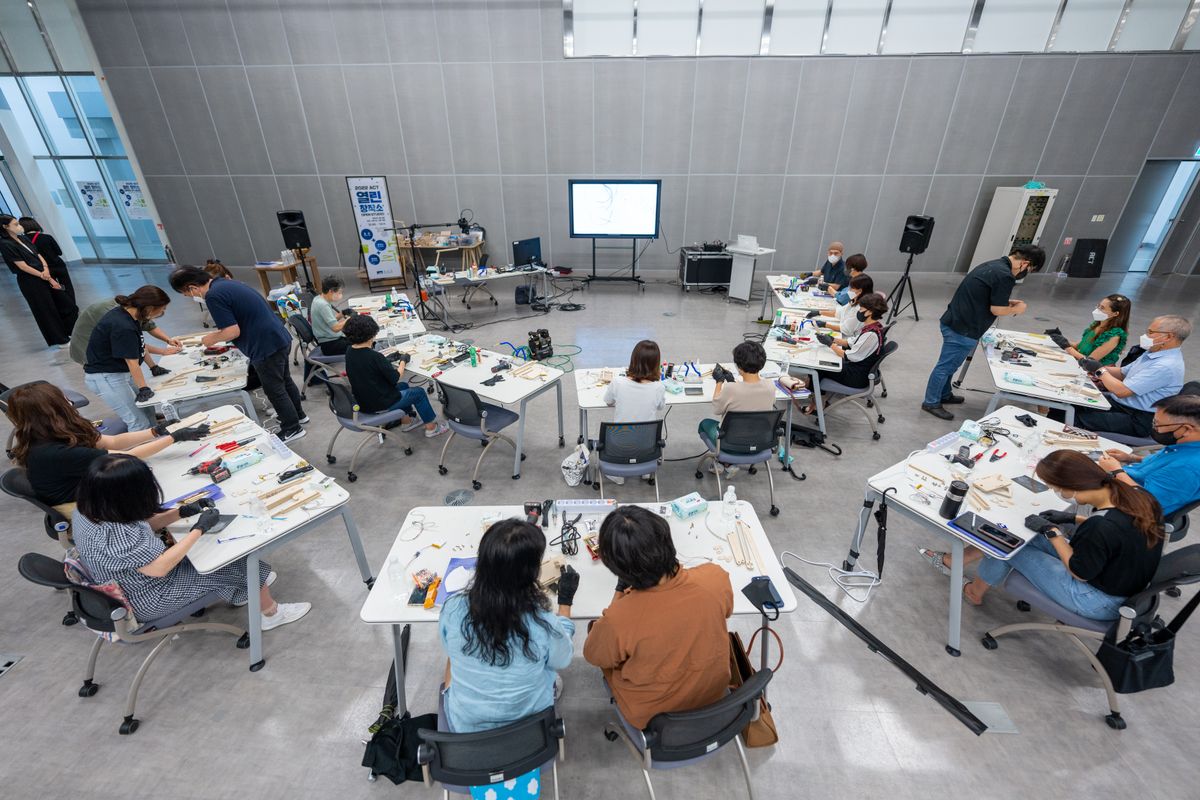 Adultes en atelier pratique autour de tables, exemple de pédagogie expérientielle