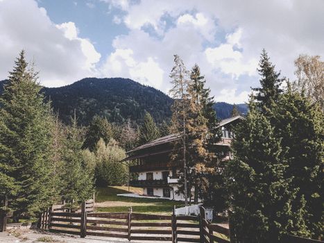 Idyllic cabin surrounded by lush forest and mountains under a vibrant sky.