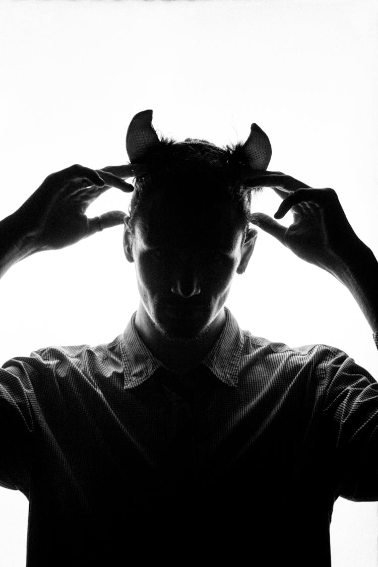 Silhouette Of Man With Devil Horns On White Background