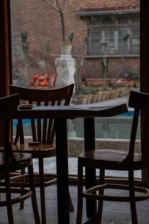 Brown Wooden Table and Chairs beside Glass Window