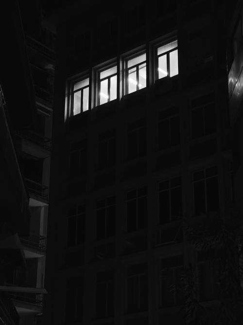 Free A dark building with an illuminated window, capturing a mysterious night scene. Stock Photo