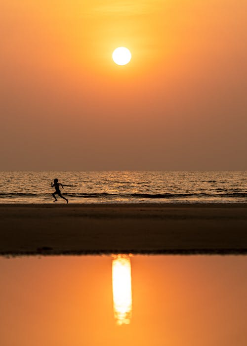 Silhouette of Person Running on the Beach during Sunset