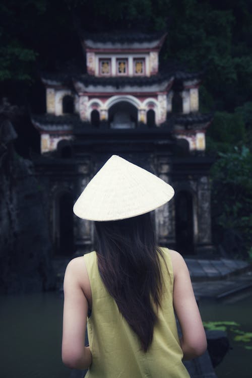 Kostnadsfri bild av asiatisk kvinna, byggnadsexteriör, hatt