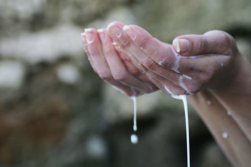白い液体で覆われた人の手