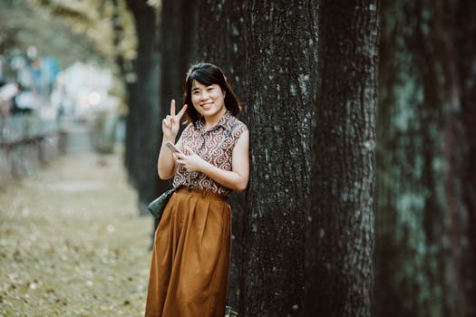 Cheerful woman posing with a peace sign in a tranquil park setting.