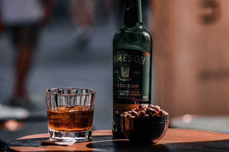 Bottle Of Jameson Wiskey, Glass And Hazelnuts On A Table