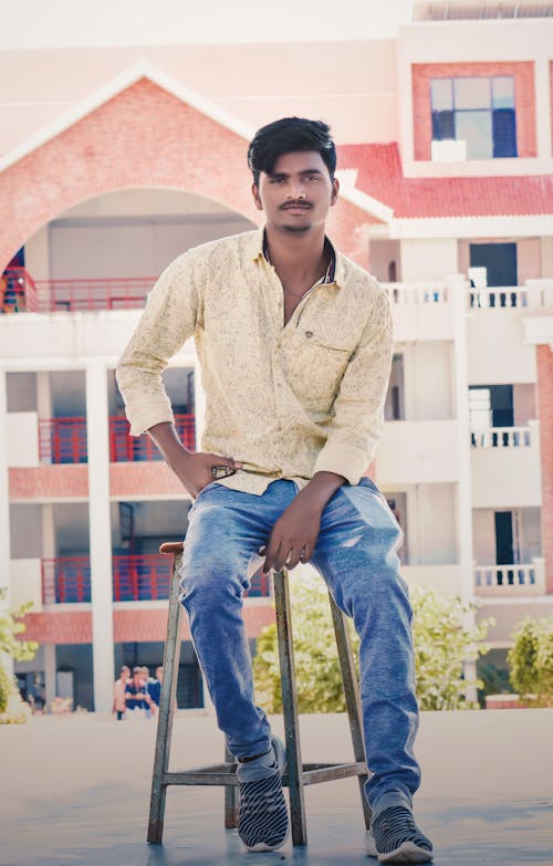 A Guy Sitting On Chair Behind A Building