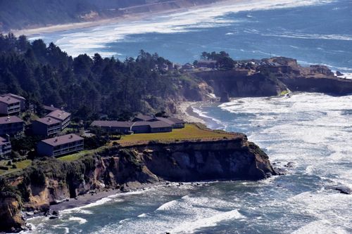 Free Aerial view of oceanfront homes atop a picturesque cliff overlooking a scenic coastline. Stock Photo