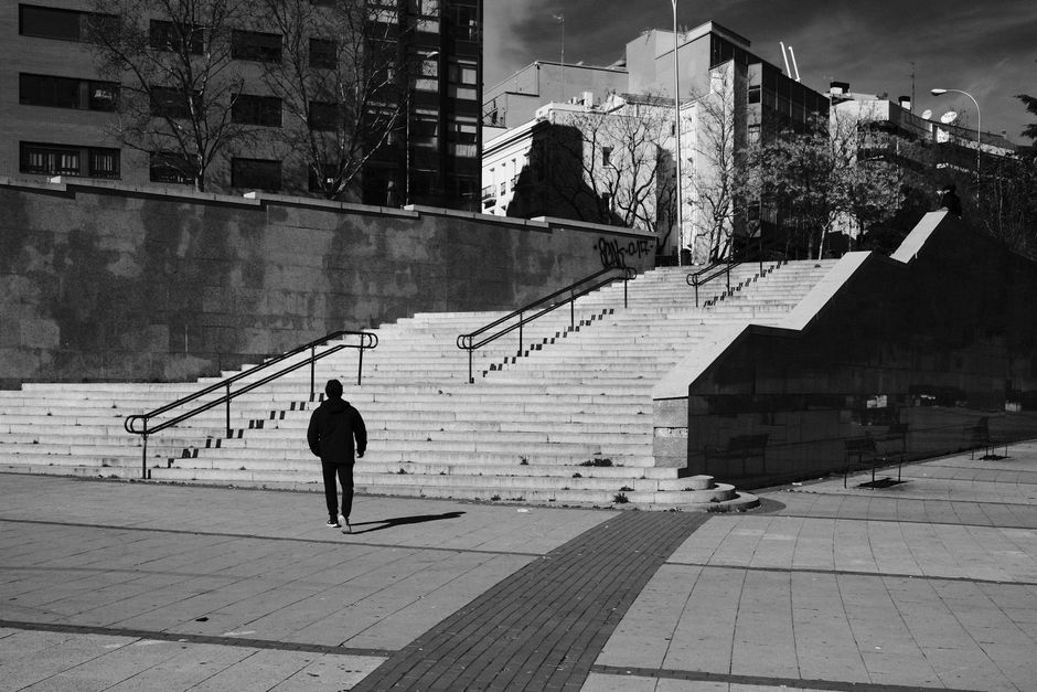 Una persona sube escaleras en un entorno urbano en Madrid, España, capturada en blanco y negro.