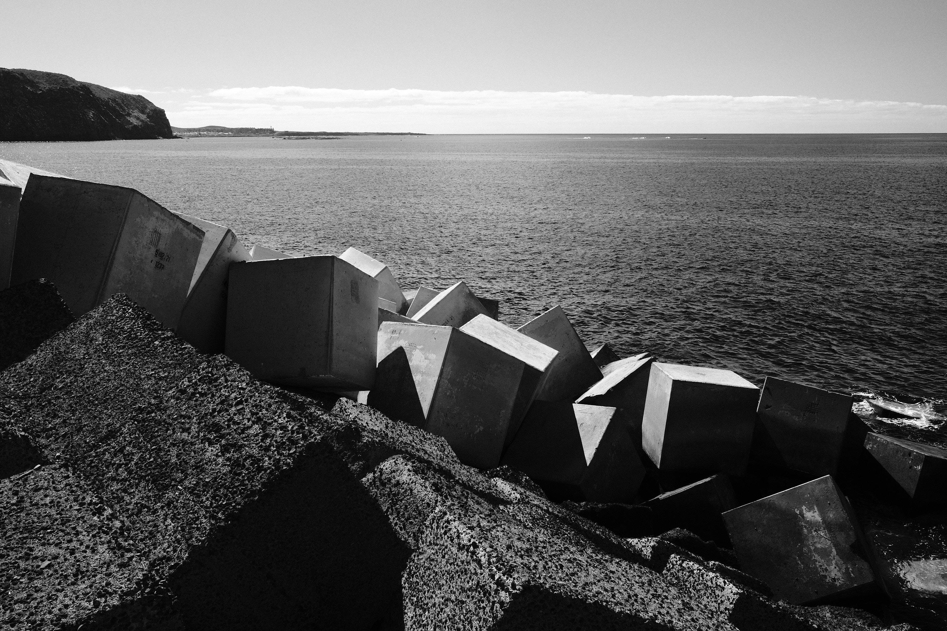 grayscale photo of concrete boxes on the shore