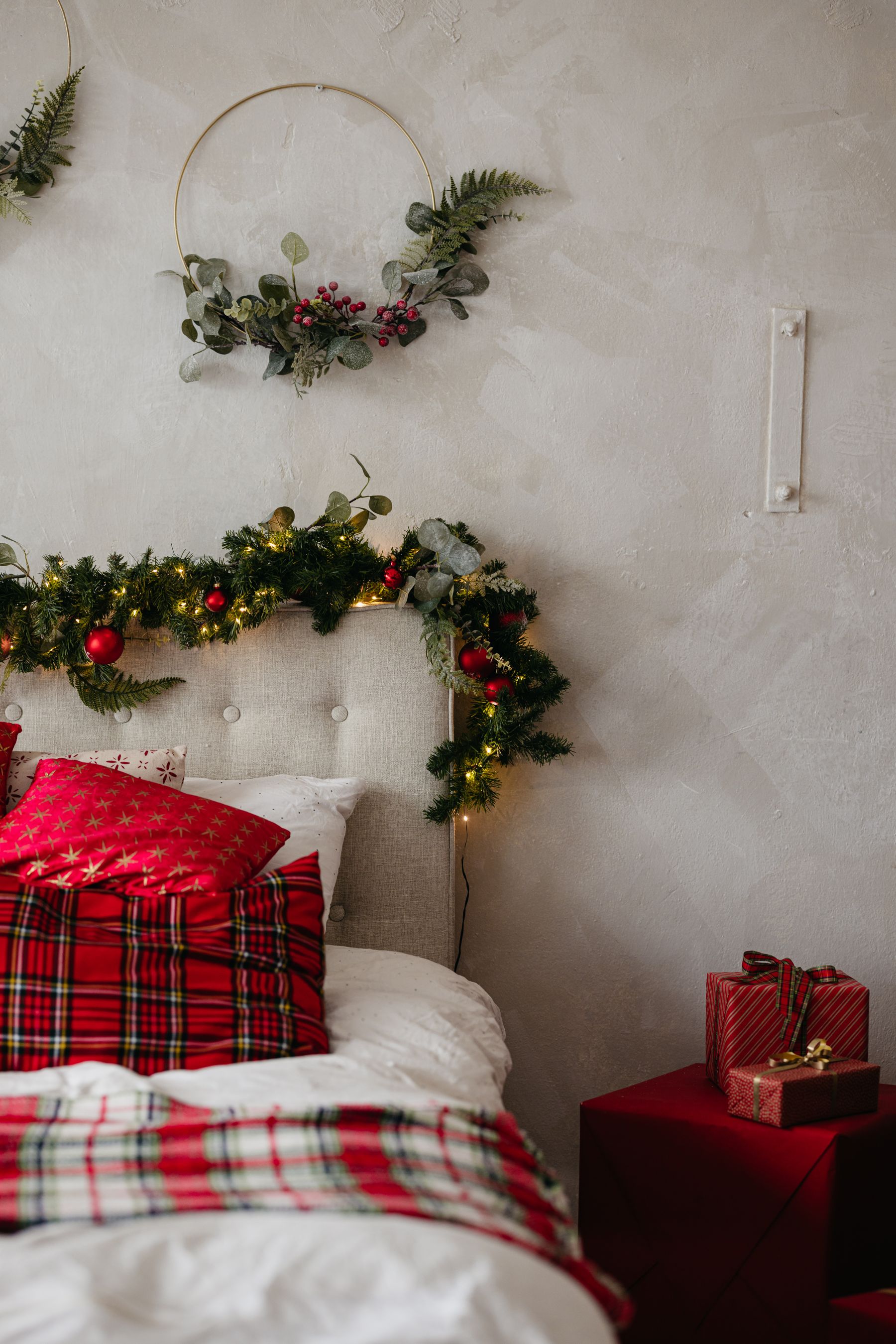 Christmas bedroom with plaid pillows greenery wrapped gifts and a cozy bed