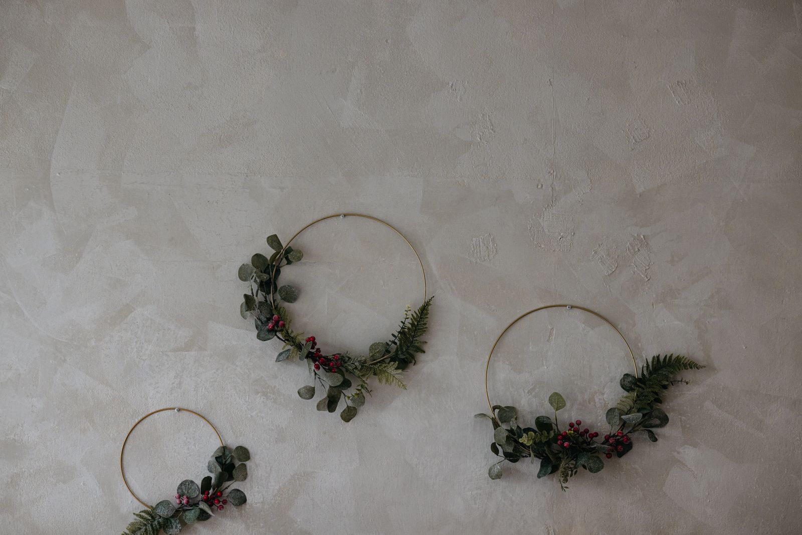 christmas wall decor ideas: elegant minimalist wreaths with red accents on a textured wall