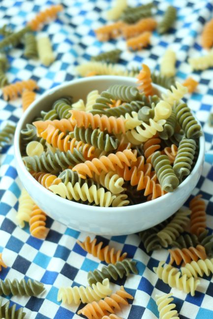 A pile of dried fusilli corkscrew pasta spirals on a wooden board, showing the tight ridged twists.