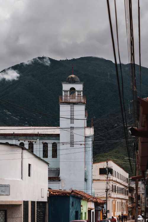 Free Stunning view of Mérida's cityscape featuring a church tower against mountainous scenery under cloudy skies. Stock Photo