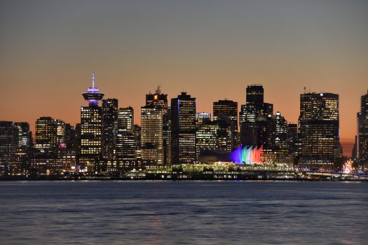 Vancouver's vibrant skyline at dusk with colorful reflections on the water.