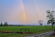 日落时分，乡村的绿色牧场和泥土小路上出现了一道美丽的双彩虹