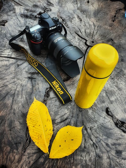 Black Nikon Dslr Camera Beside Yellow Plastic Jug