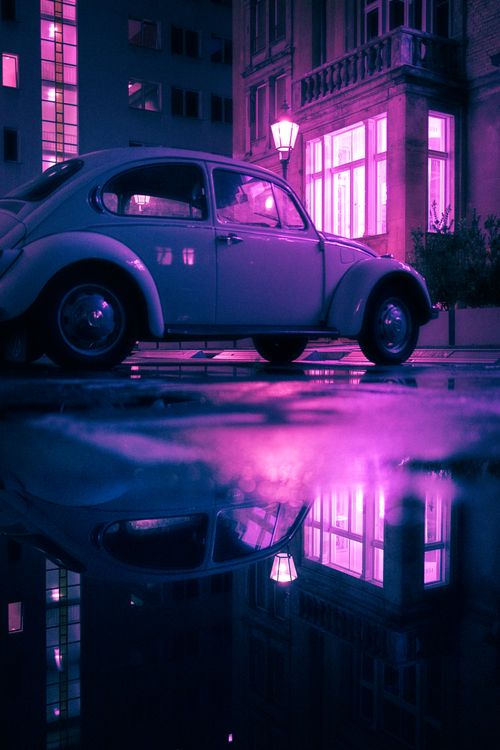 Free Classic Volkswagen Beetle reflecting in puddle amid Berlin's vibrant neon colors. Stock Photo
