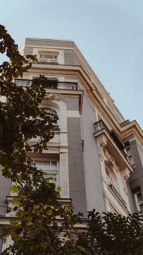 Free A low-angle view of a stylish residential building showcasing architectural details and greenery in an urban setting. Stock Photo
