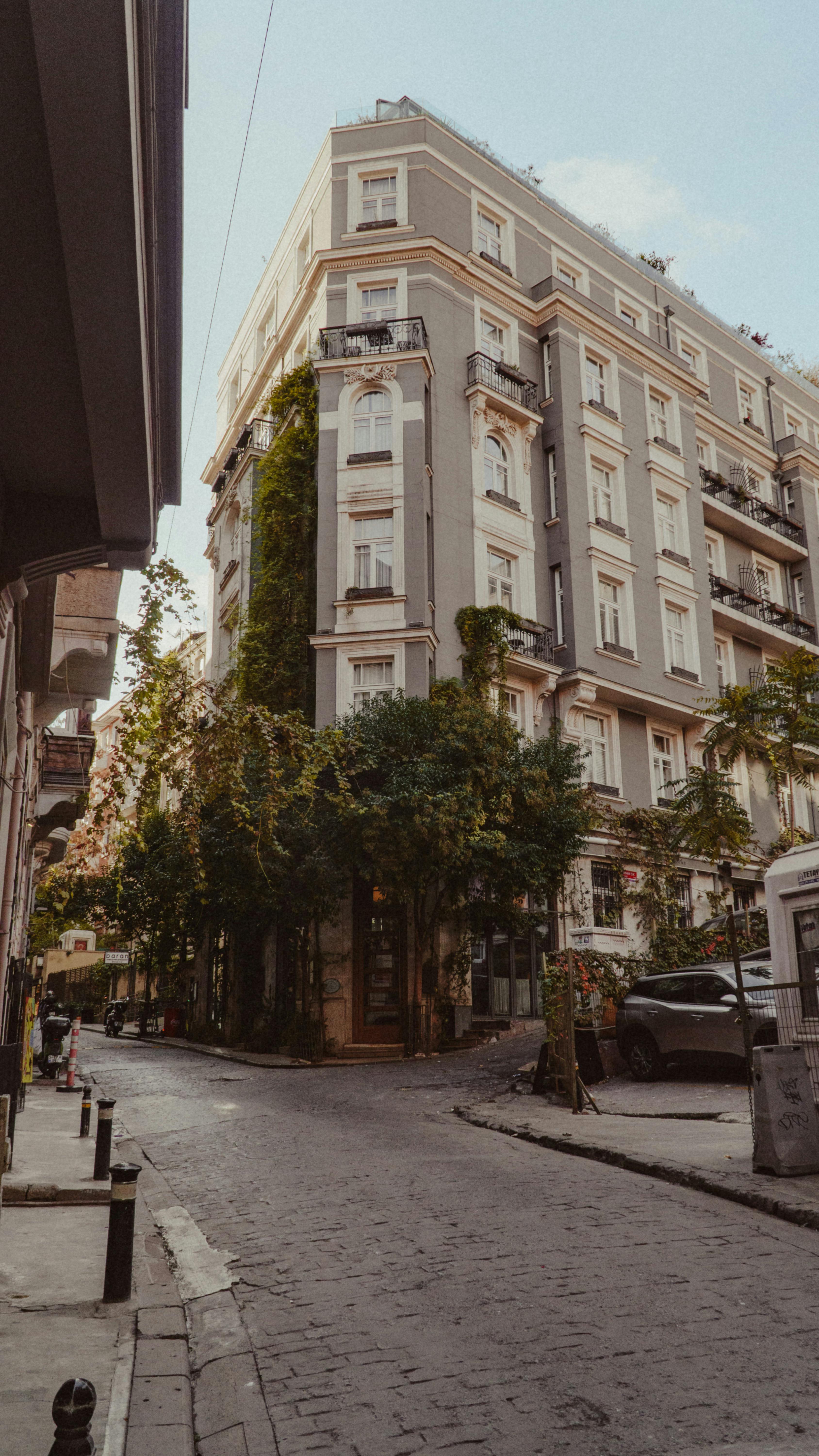 Free A picturesque street corner featuring classic architecture and lush greenery, perfect for urban lifestyle themes. Stock Photo