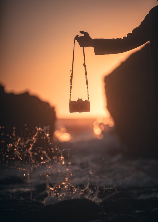 Silhouette of Person Hand with Camera on Sunset