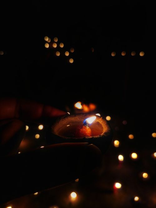 Free A close-up of a single candle against a backdrop of blurred lights, creating a serene atmosphere. Stock Photo