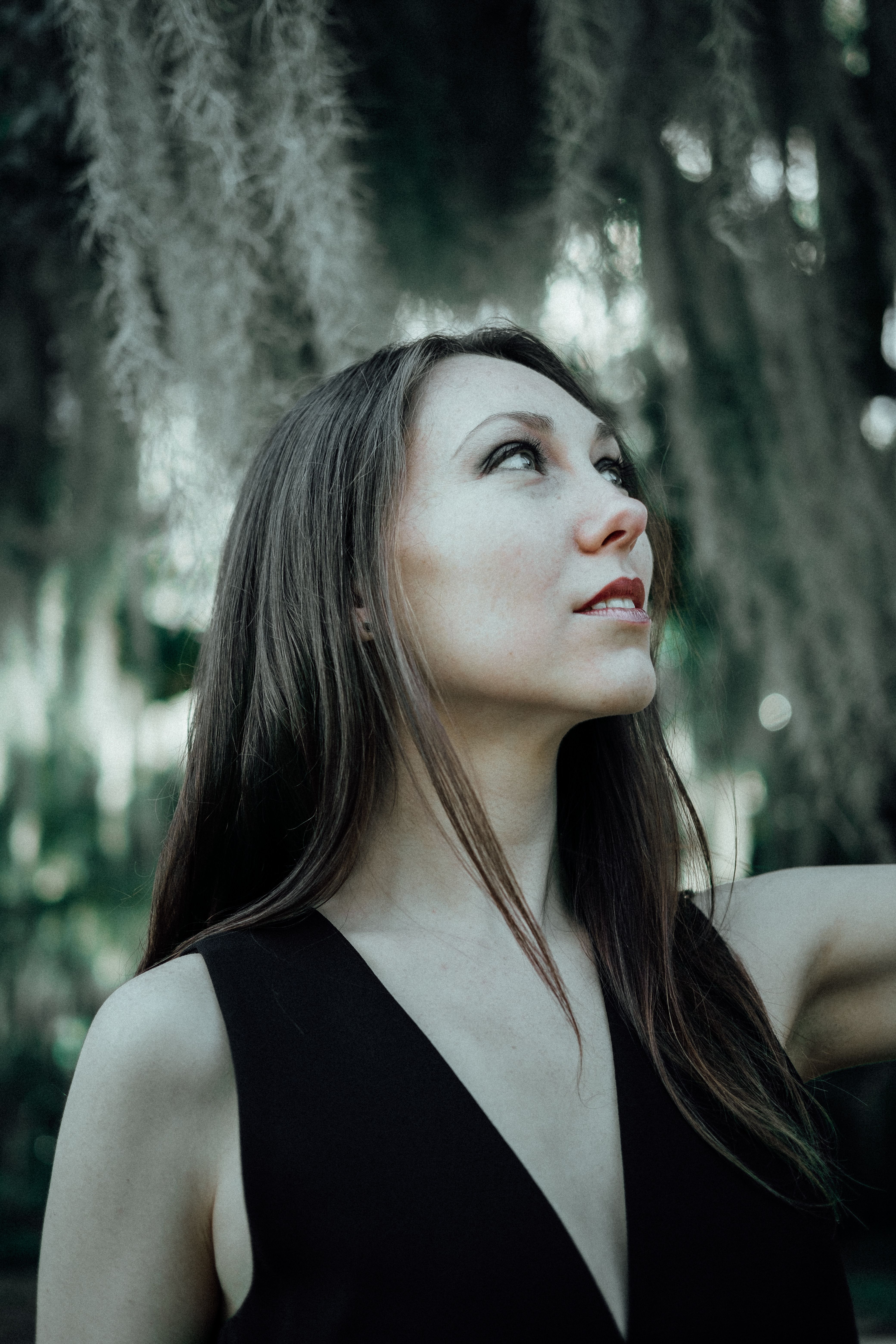 Portrait of a woman gazing upward amidst lush greenery, evoking introspection.