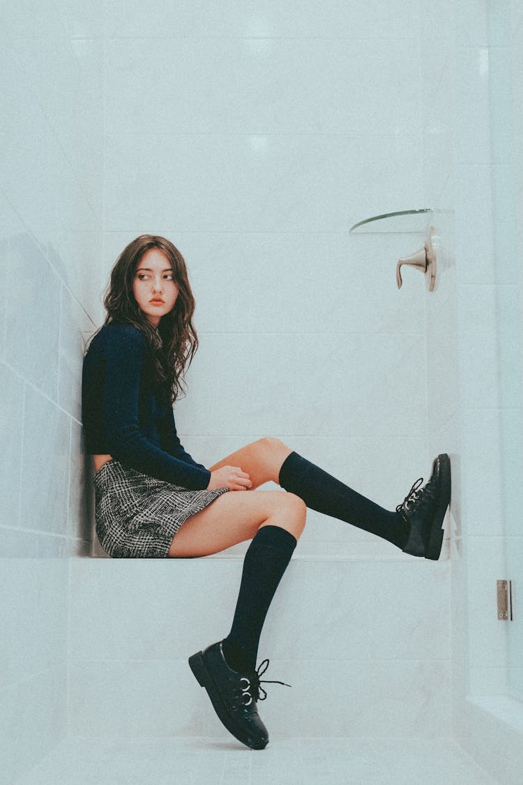 Teen Girl Sitting In White Bathroom