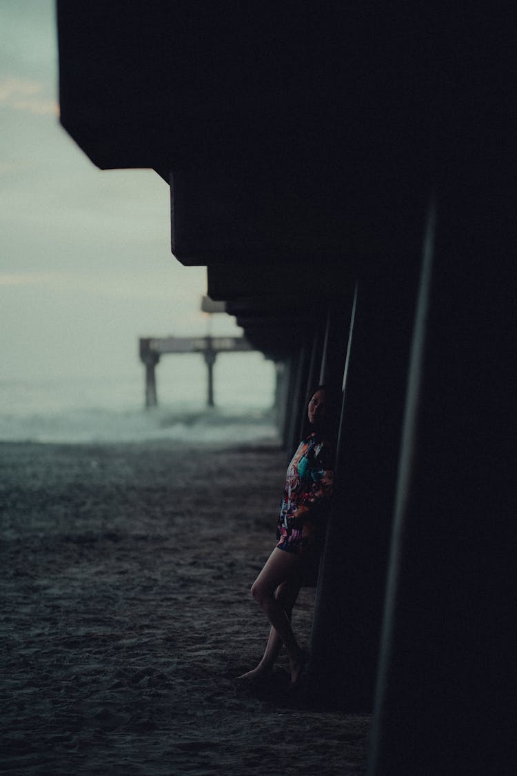 Woman Posing Near Pier At Shore In Dark