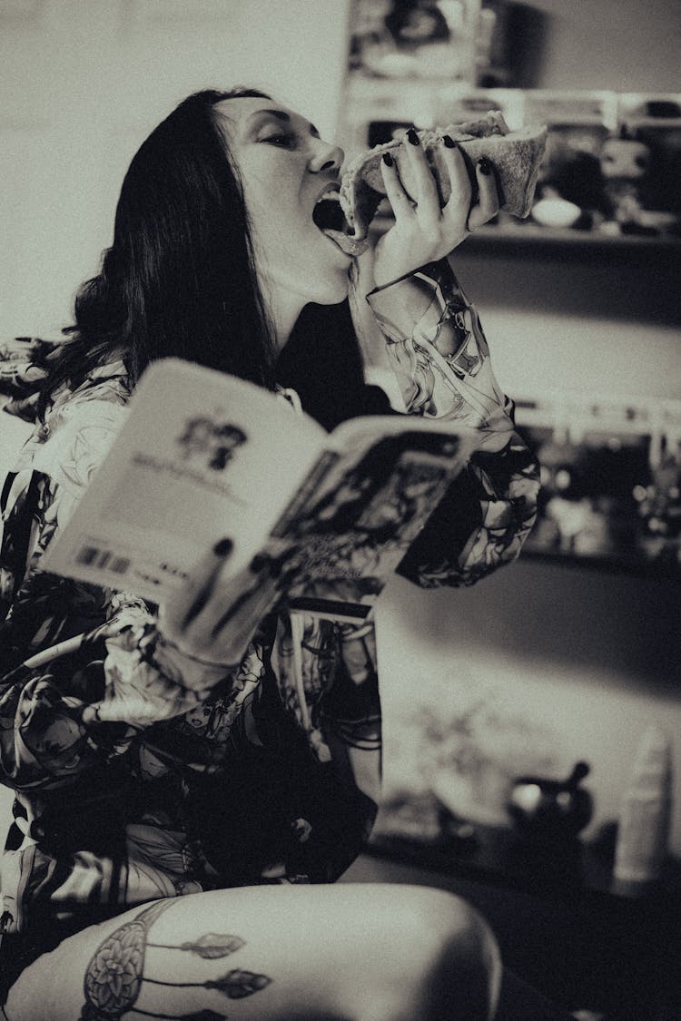 Woman Eating And Reading Book Indoors