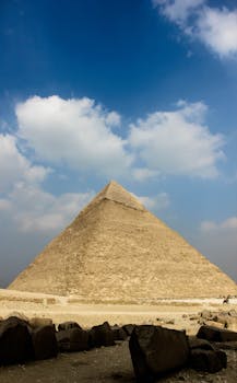 A majestic view of the Great Pyramid of Giza under a bright blue sky, capturing its ancient grandeur.