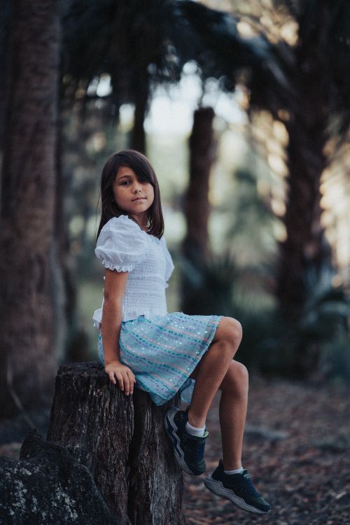 Young Girl Sitting on a Tree Stump in a Forest · Free Stock Photo