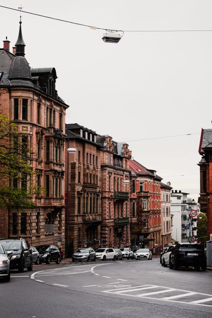 Historic Stuttgart street with vintage buildings and parked cars on a cloudy day.