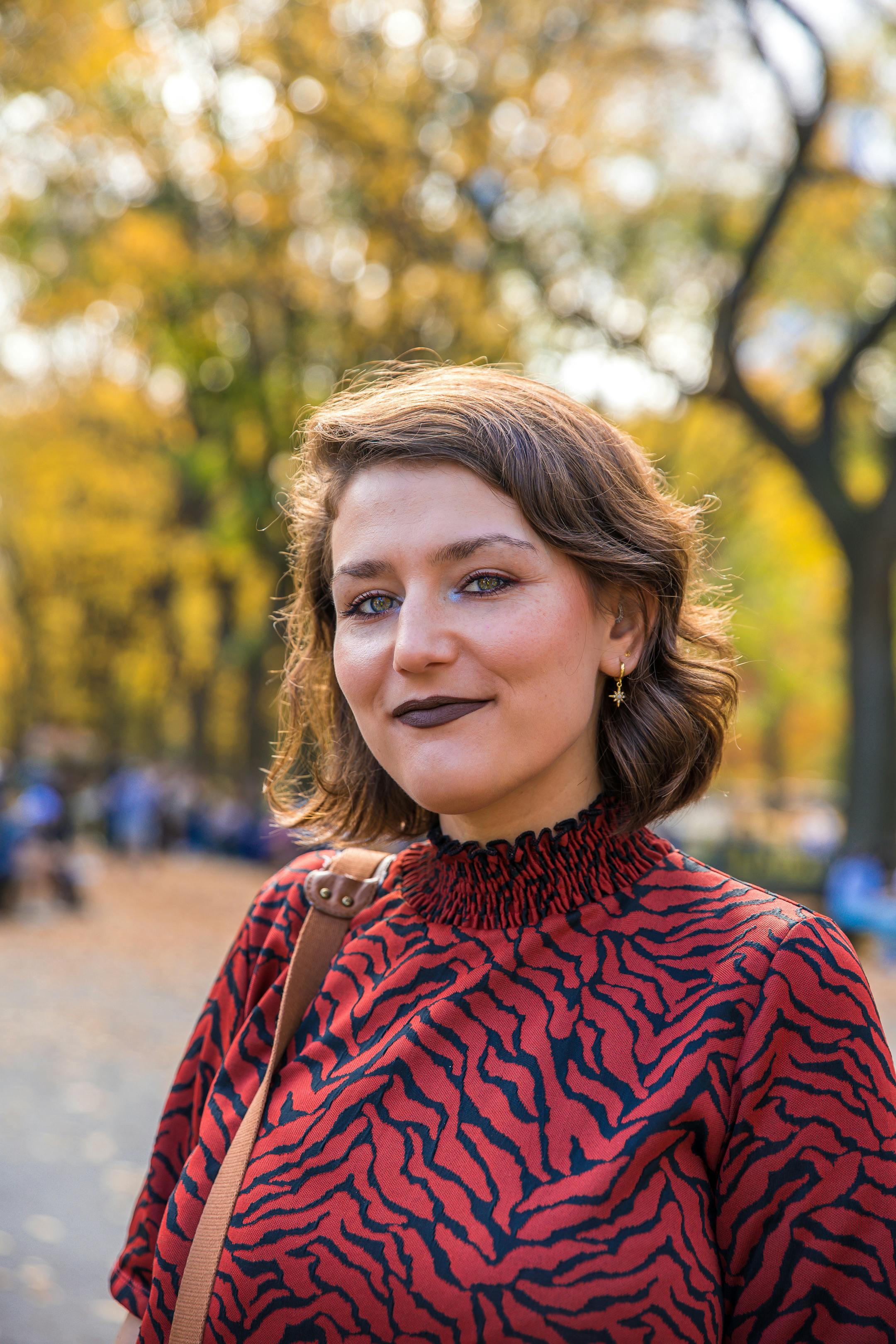 Fashionable woman in autumn park setting, New York City. Bright and cheerful atmosphere.
