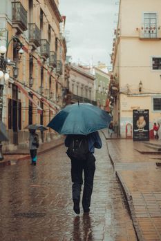 Person walking with umbrella on a rainy day in Guanajuato, Mexico's historic city streets.