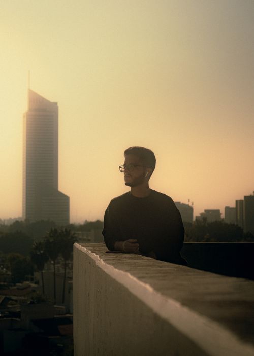 Free Silhouette of a man on a rooftop overlooking a cityscape at sunset with skyscrapers. Stock Photo
